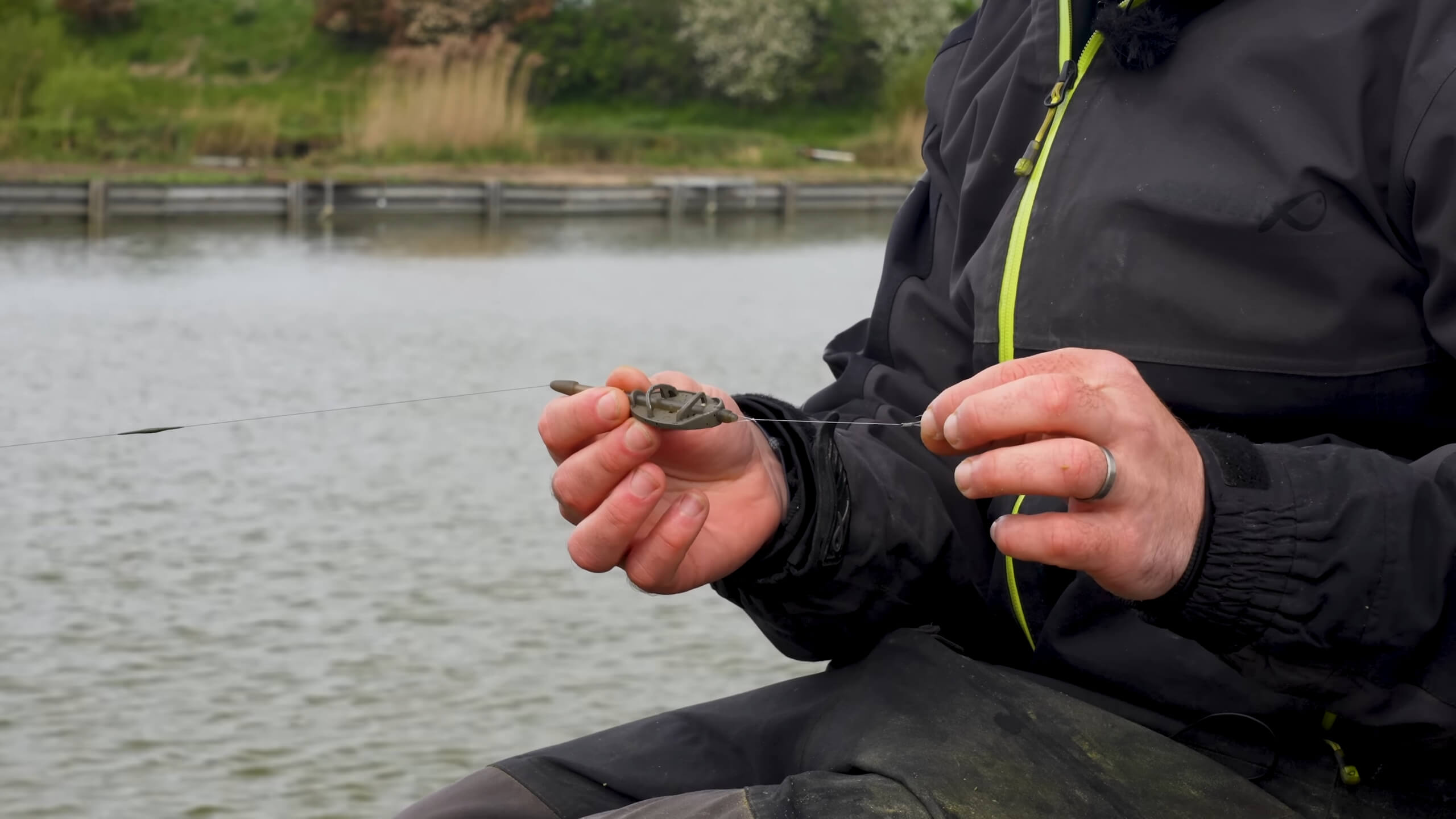 The man is setting up a rig for using the feeder fishing method